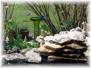 A side view of the green glass totem bird waterer