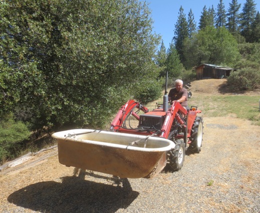 Pried out of it's spot, the tub is transported down from the goat shed